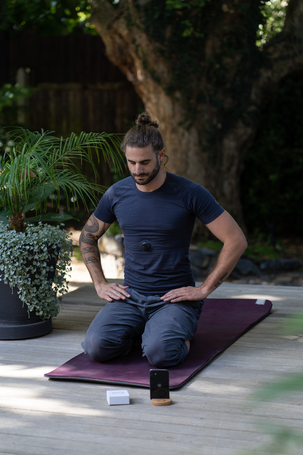 um homem sentado em um tapete de ioga com as mãos nos bolsos