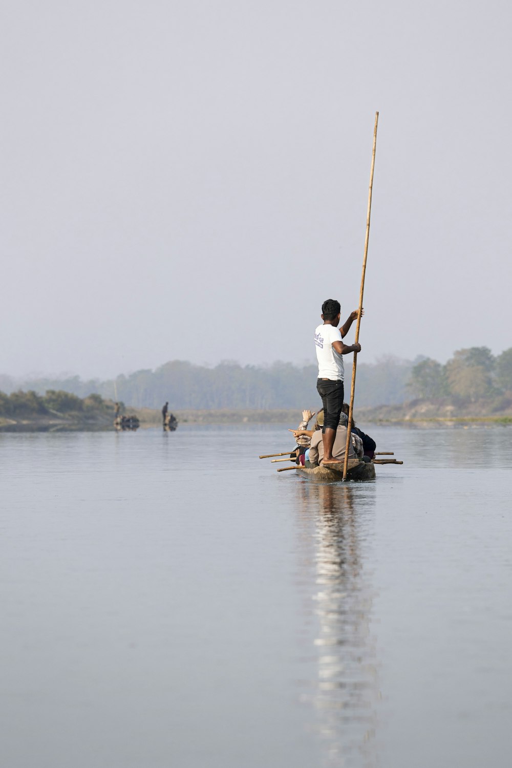 a man on a boat with a pole in the water