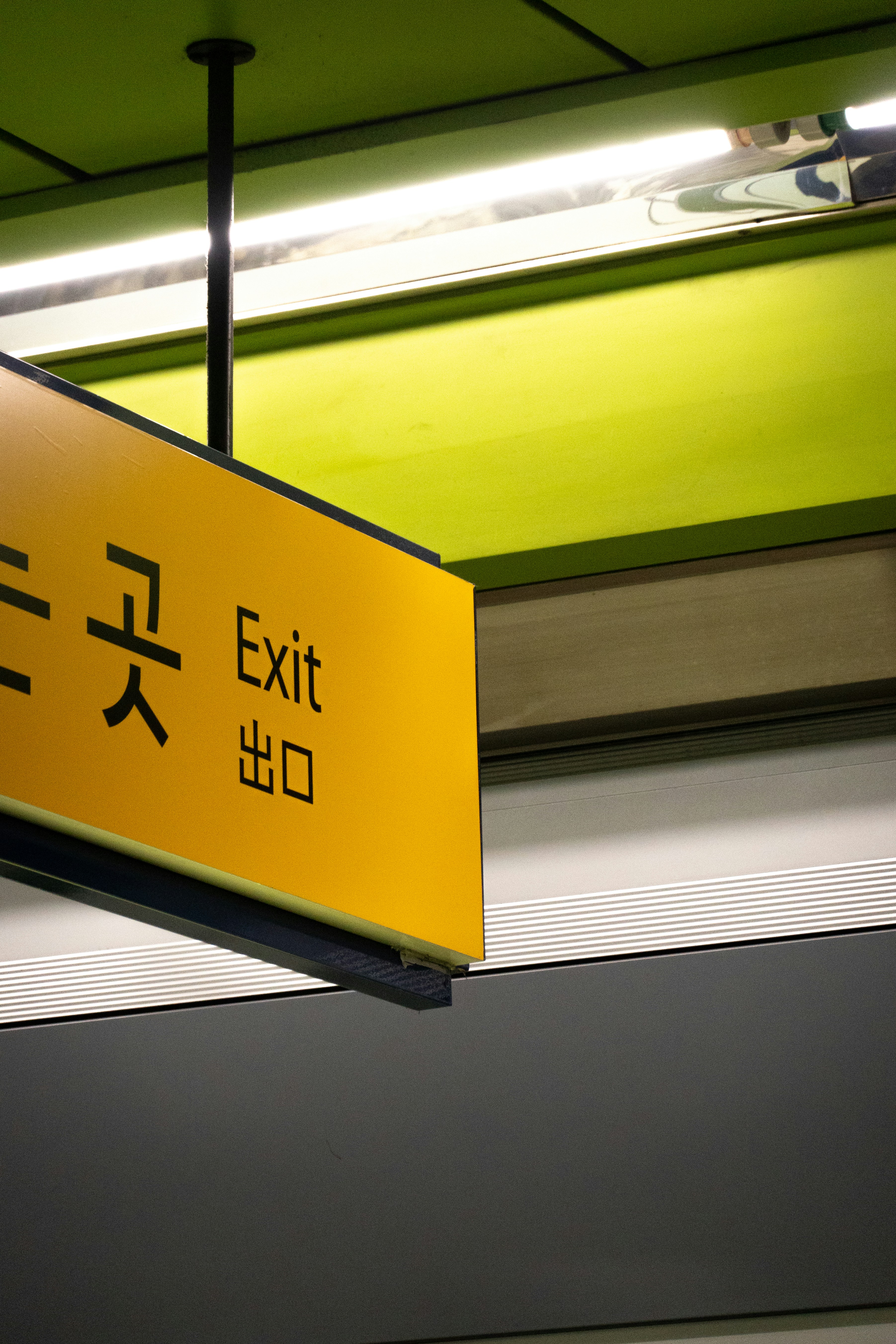 a yellow exit sign hanging from a ceiling