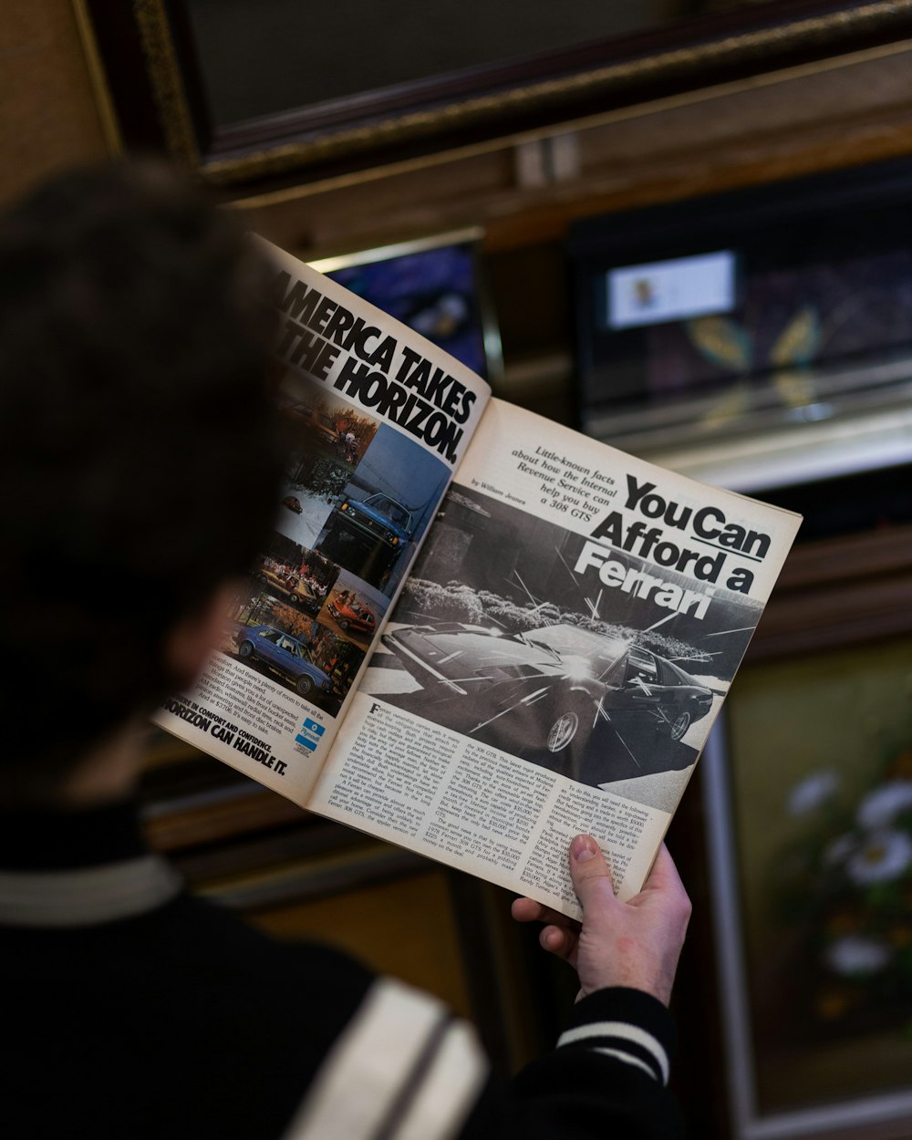 a man reading a newspaper with a picture of a car