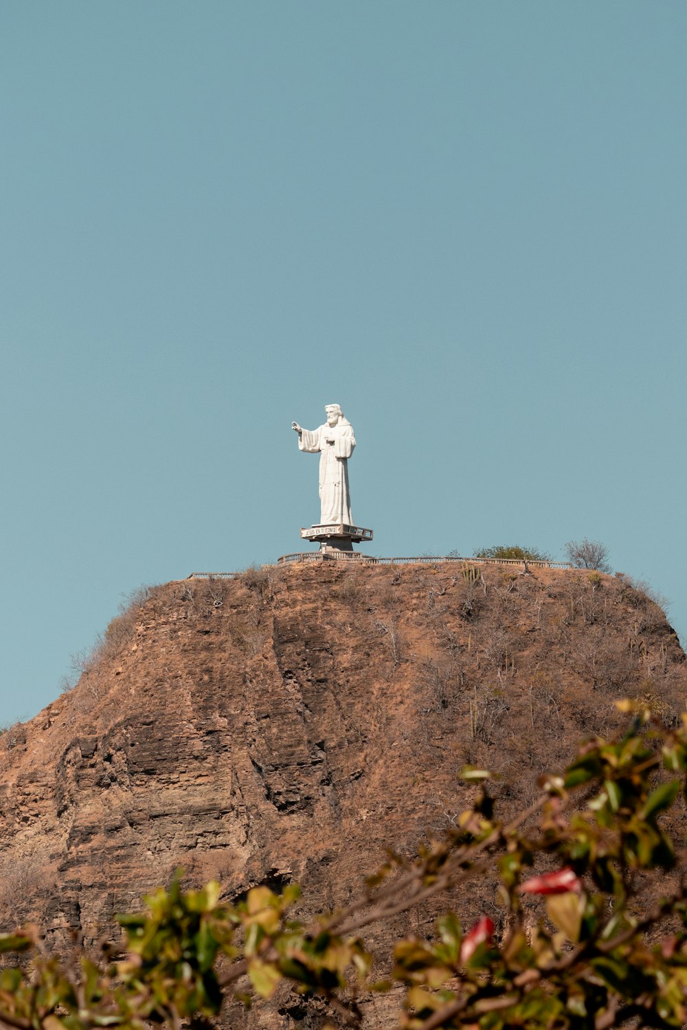 una estatua en la cima de una colina con un fondo de cielo