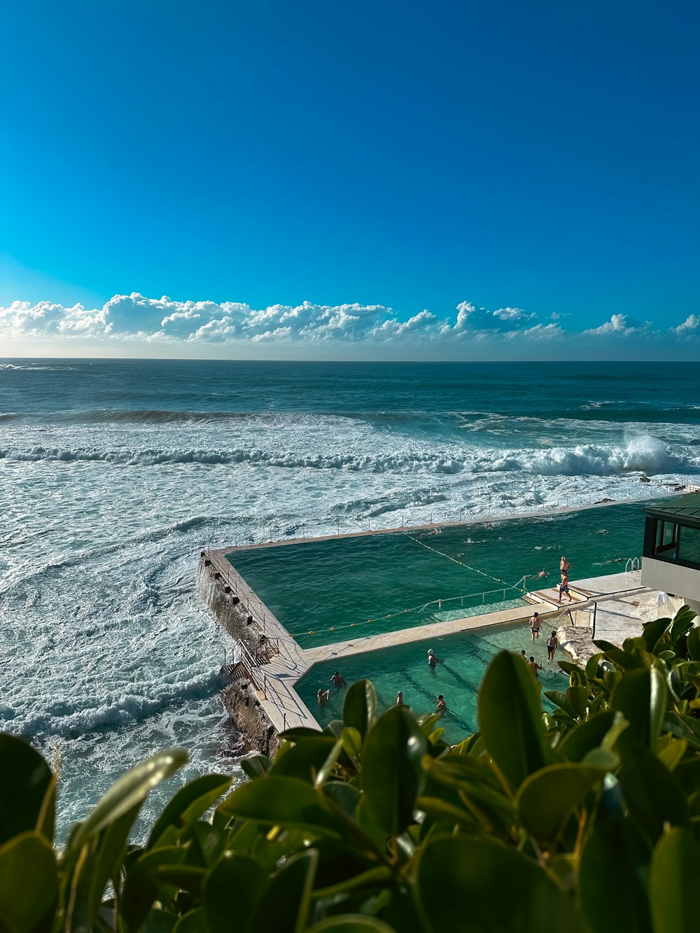 a person standing on a ledge near the ocean