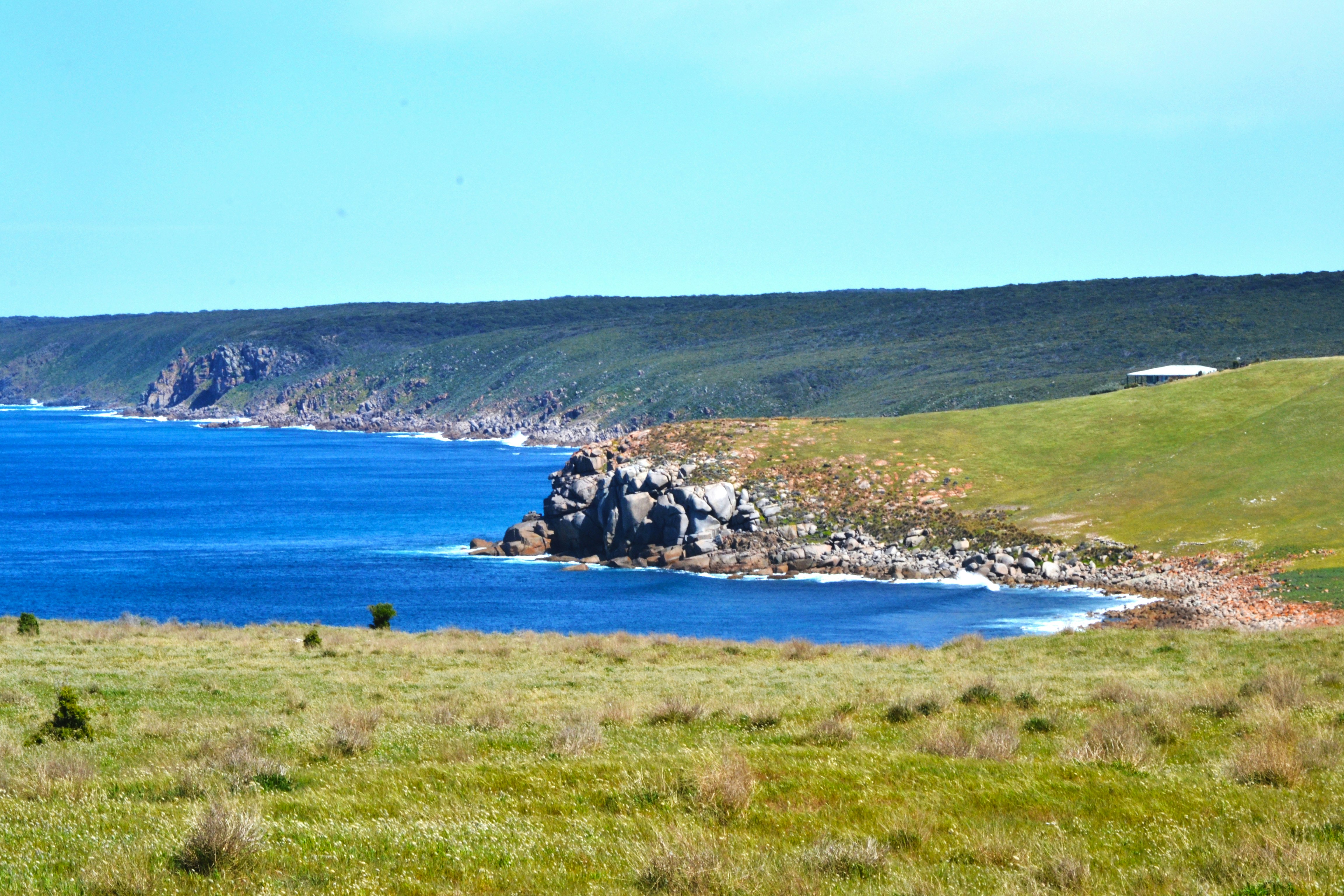 a large body of water sitting next to a lush green hillside