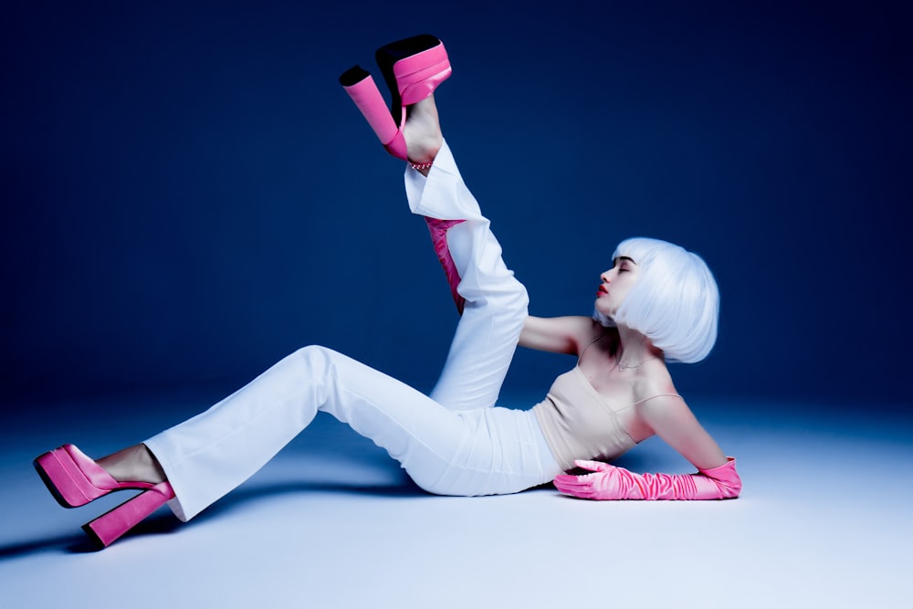 una mujer de pelo blanco y zapatos rosas tirada en el suelo