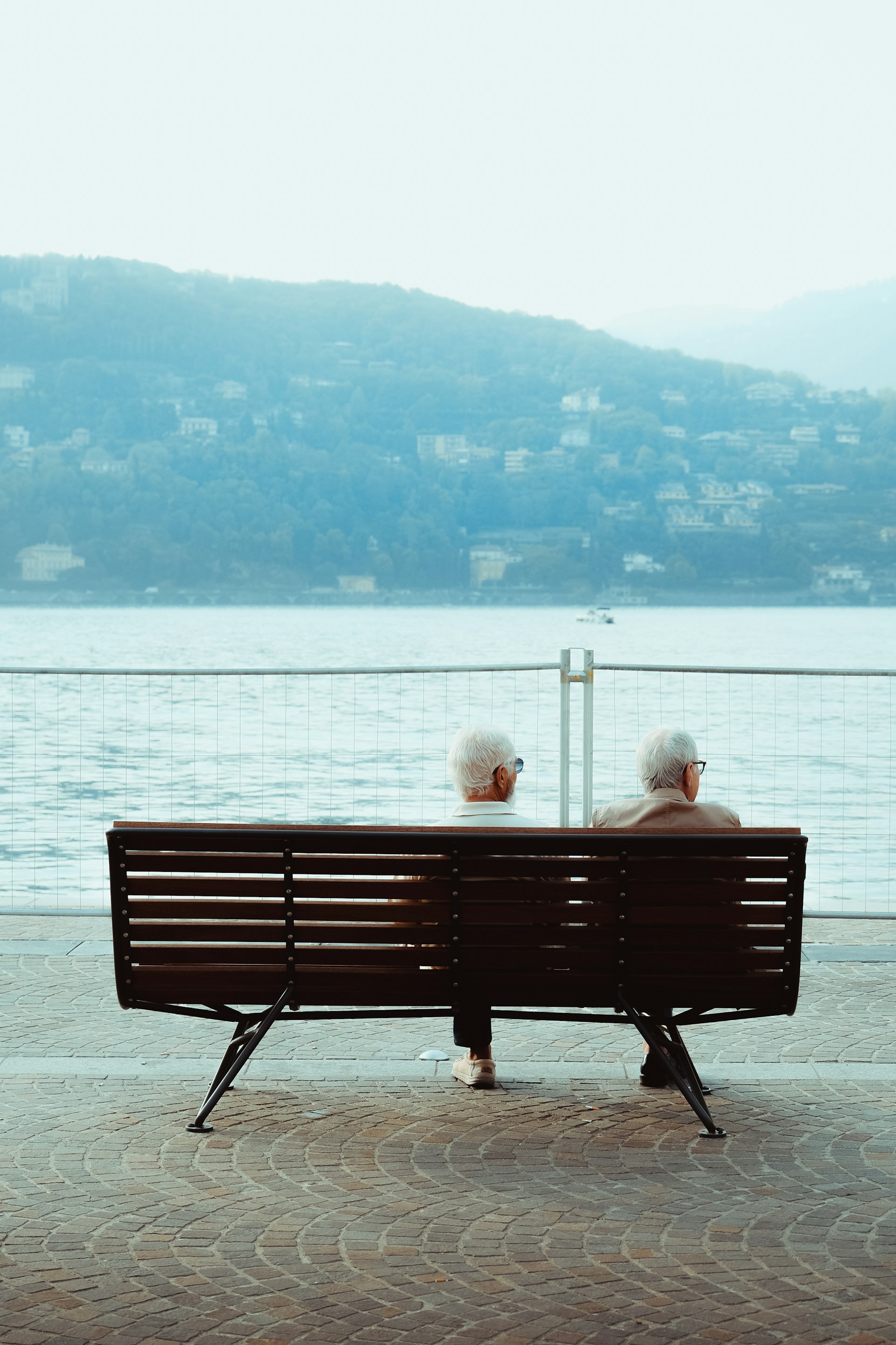 two people sitting on a bench looking out at the water