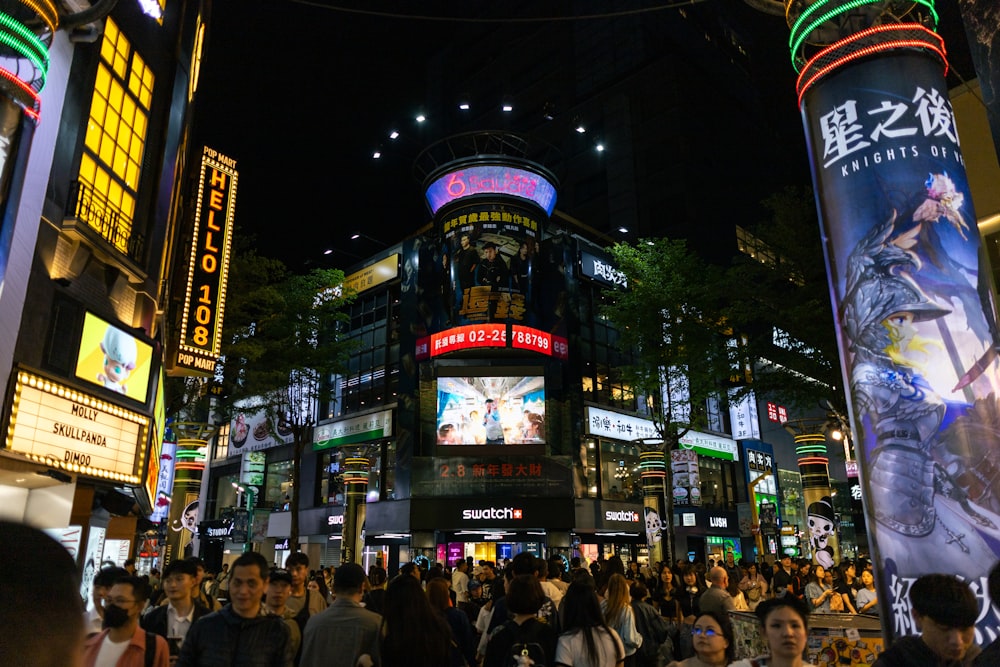 a crowd of people walking around a city at night