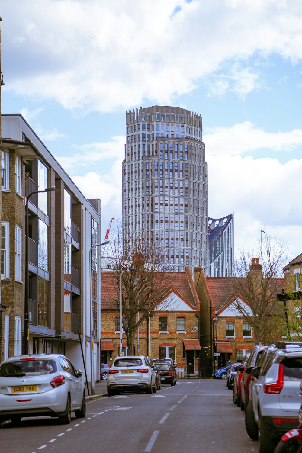 a city street lined with parked cars and tall buildings