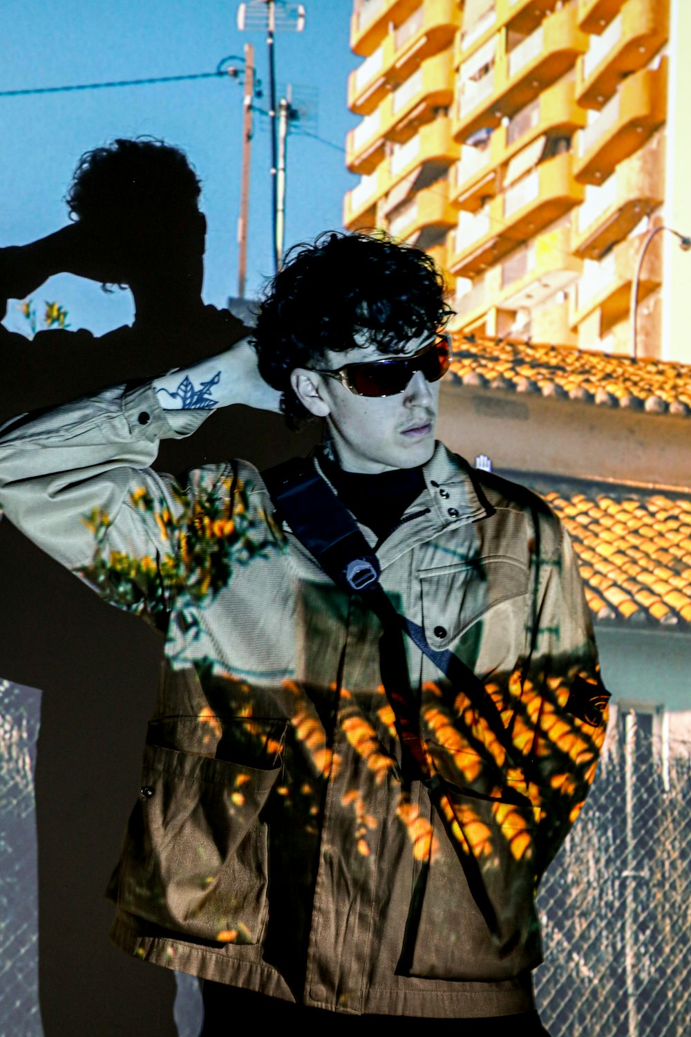 a man in a jacket and sunglasses standing in front of a building