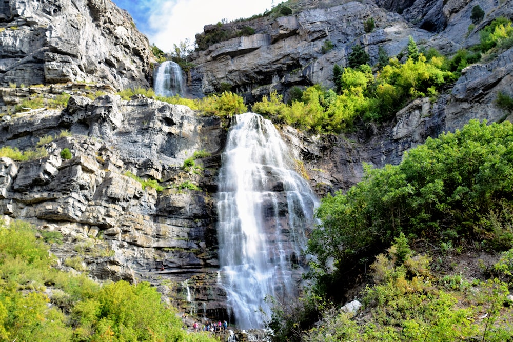 un groupe de personnes debout à la base d’une chute d’eau