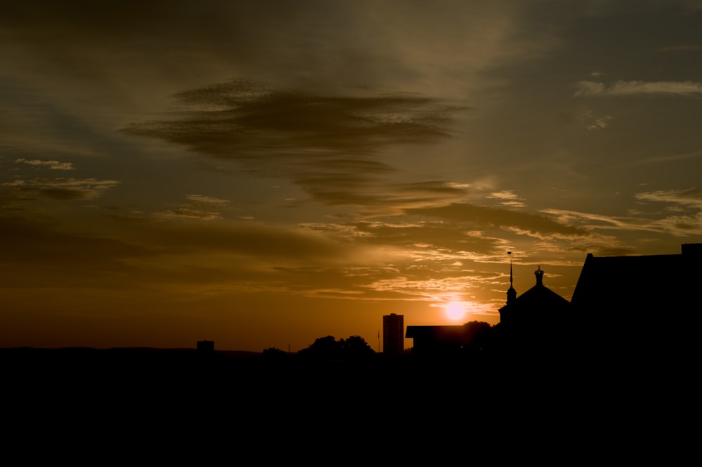 the sun is setting behind a silhouette of a building