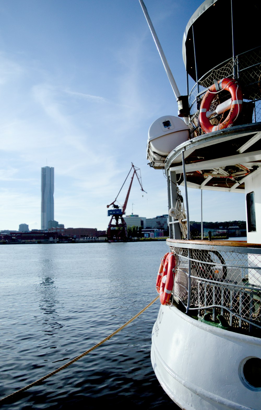 a boat docked in the water with a crane in the background