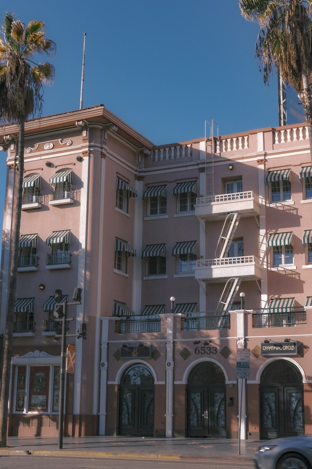 a car driving past a tall pink building