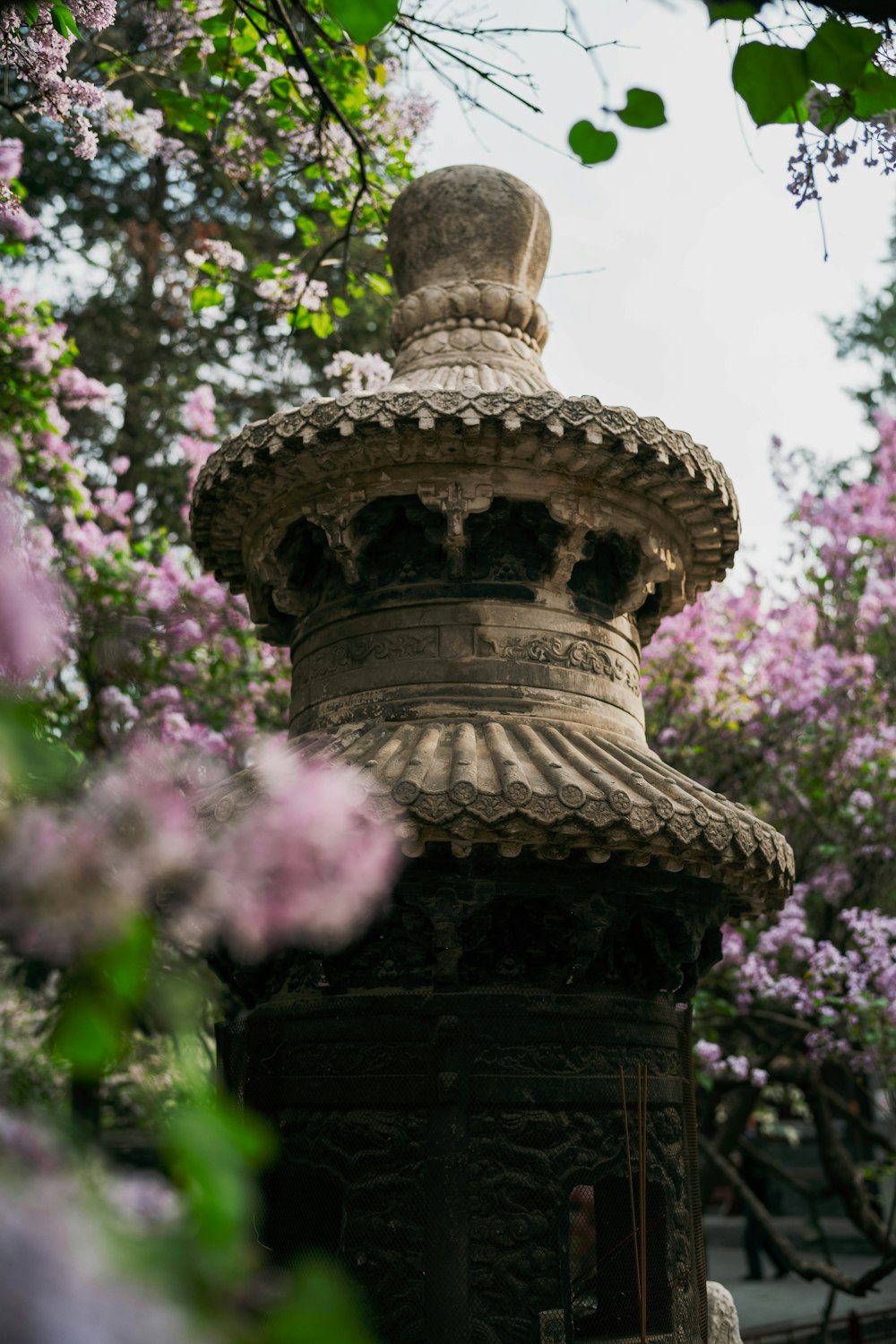 a stone structure surrounded by flowers and trees