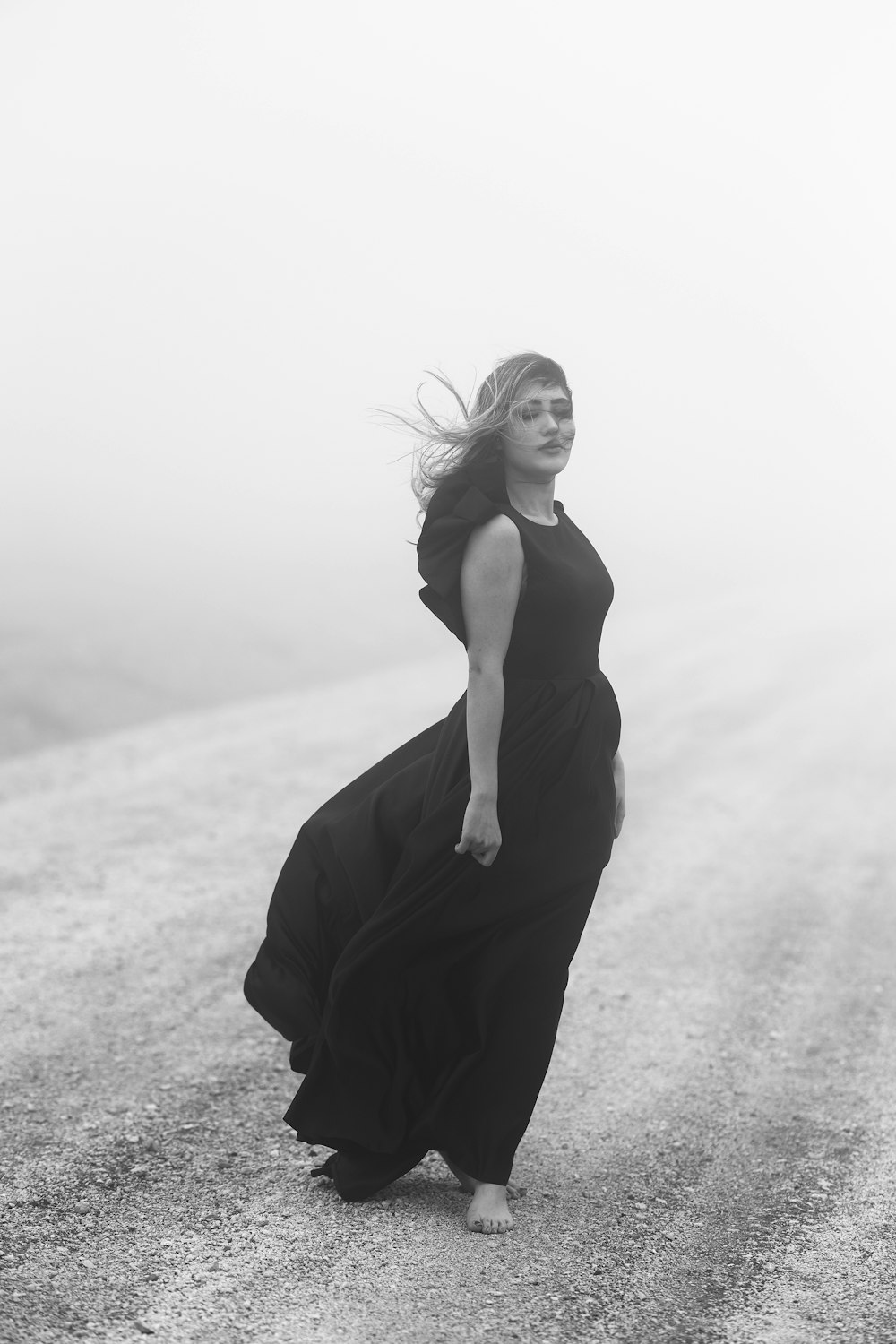 a woman in a long black dress walking down a road