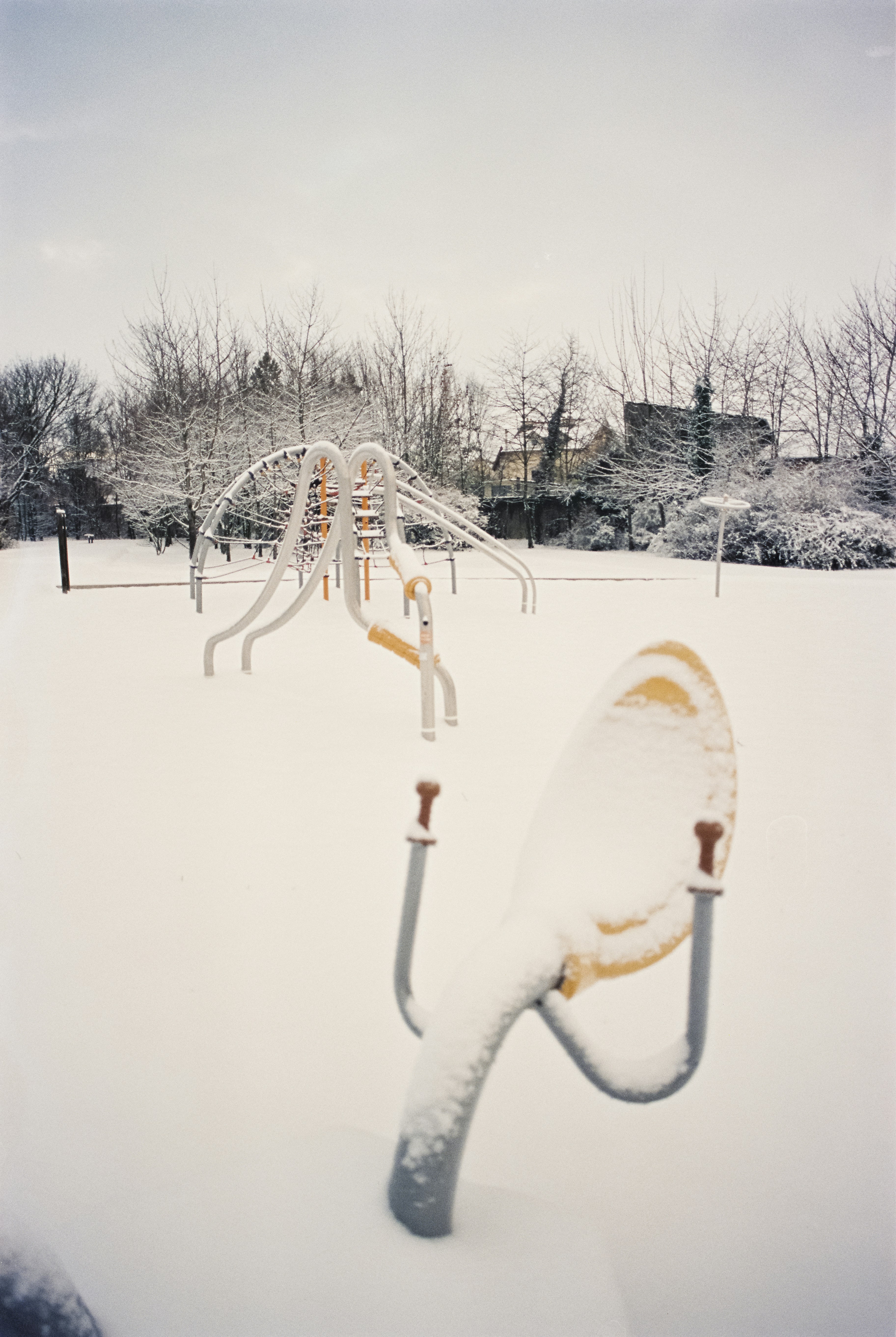 a snow covered park with a playground in the background