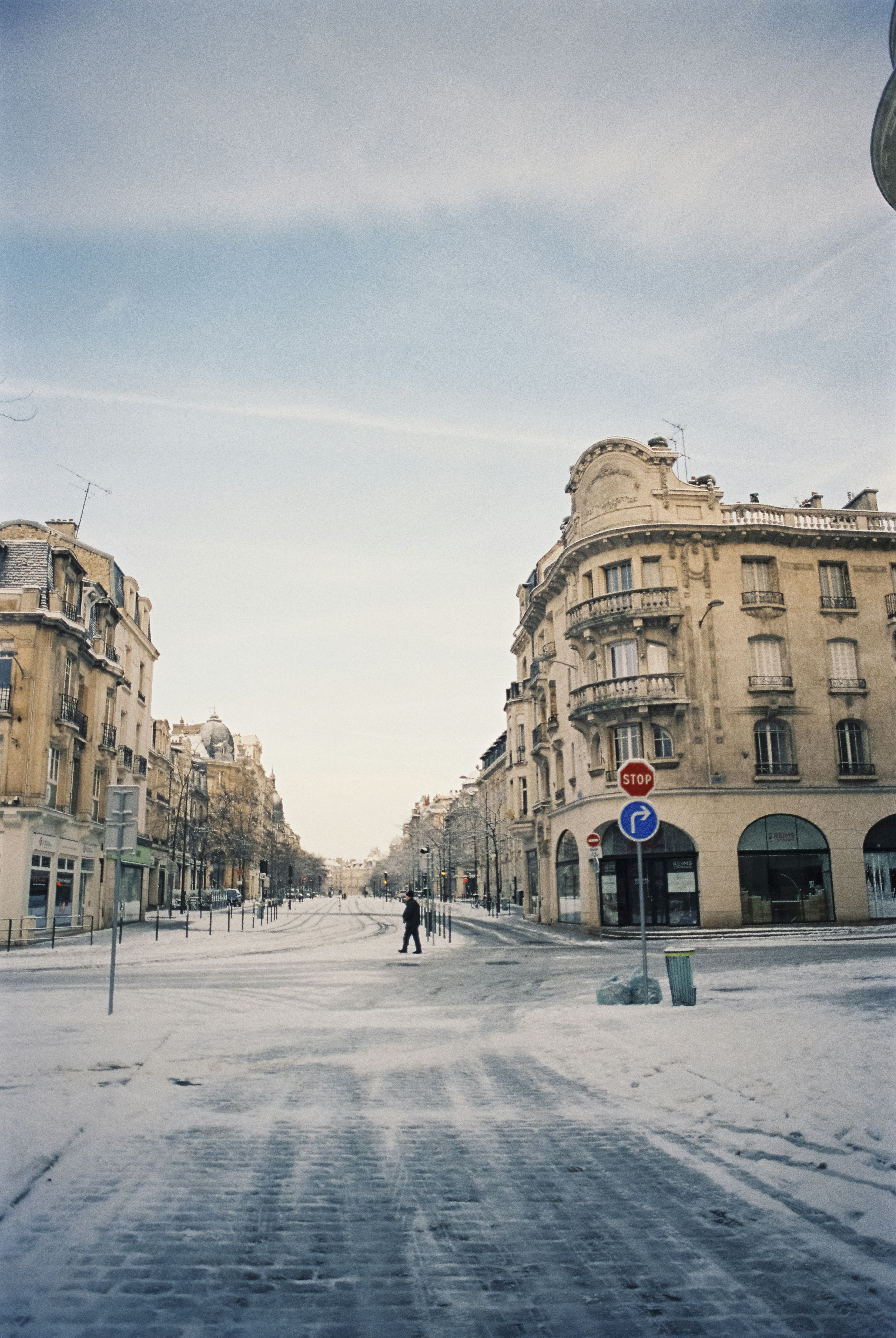 a person walking down a snowy street next to tall buildings
