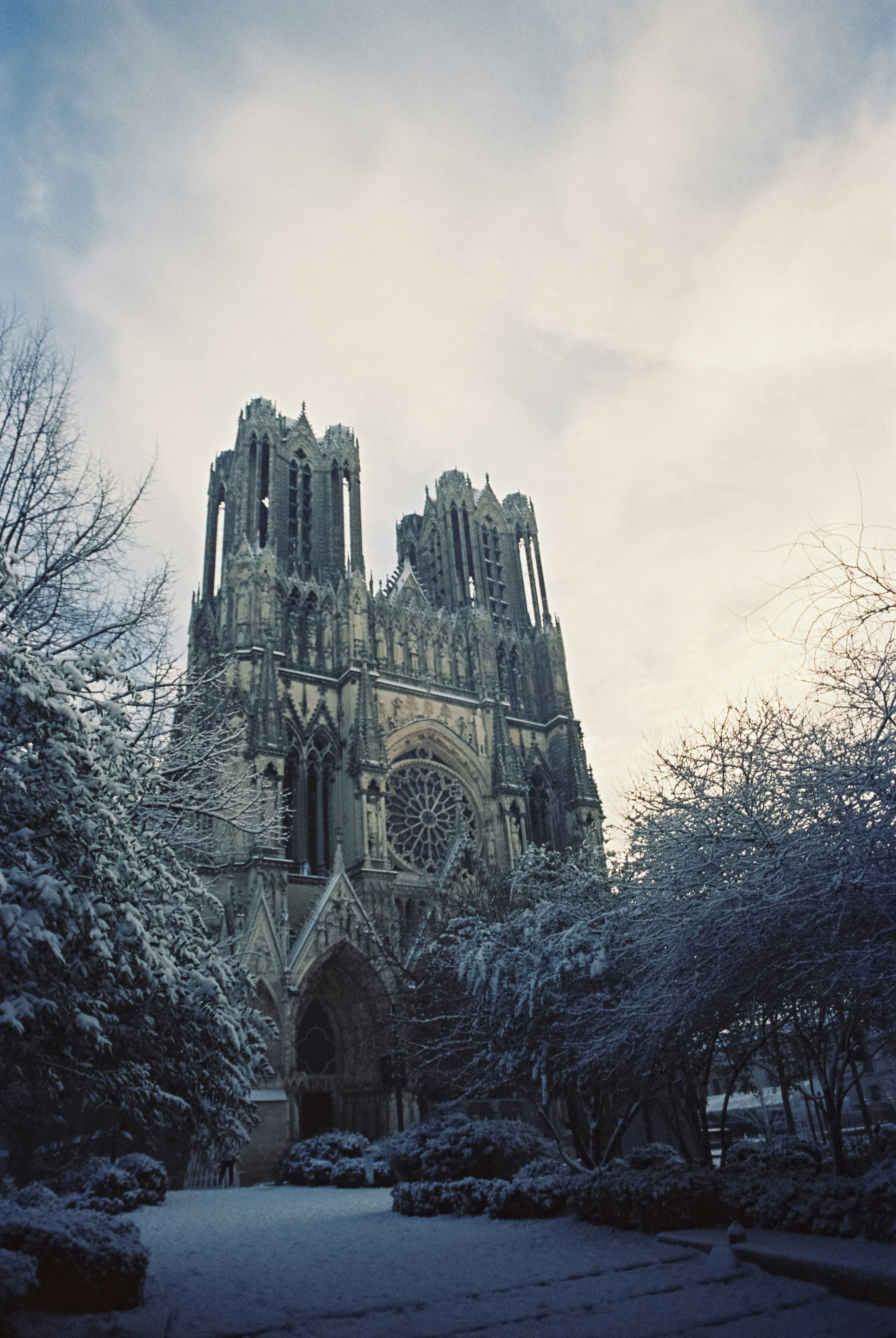 a very tall cathedral towering over a snow covered park