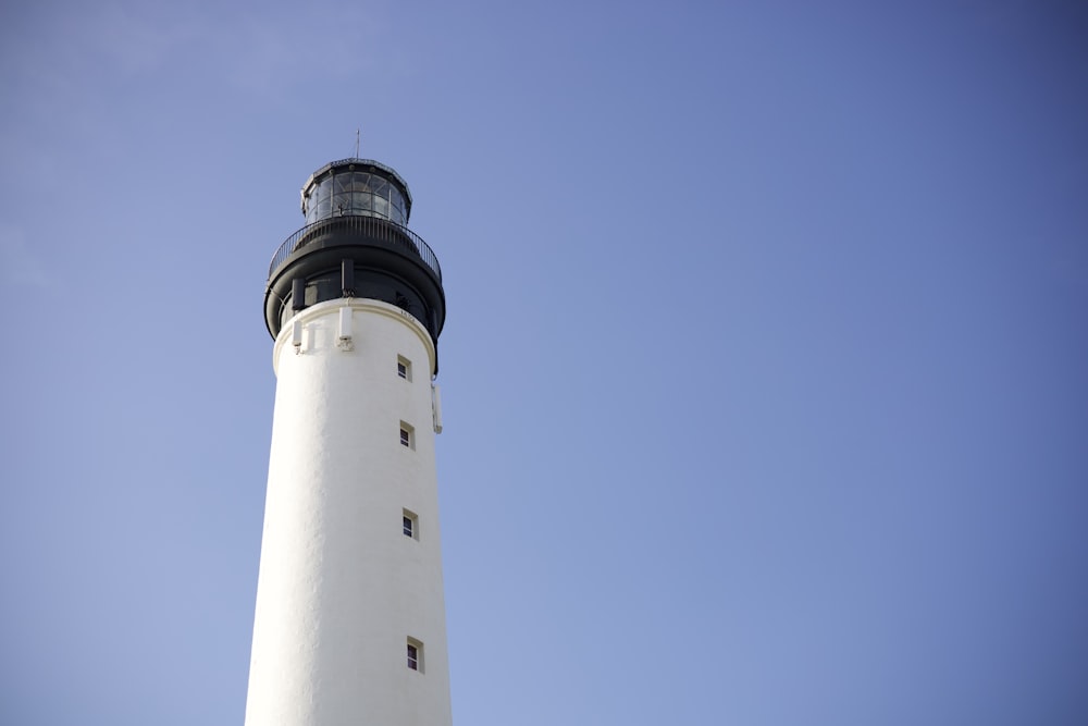 a white and black lighthouse against a blue sky