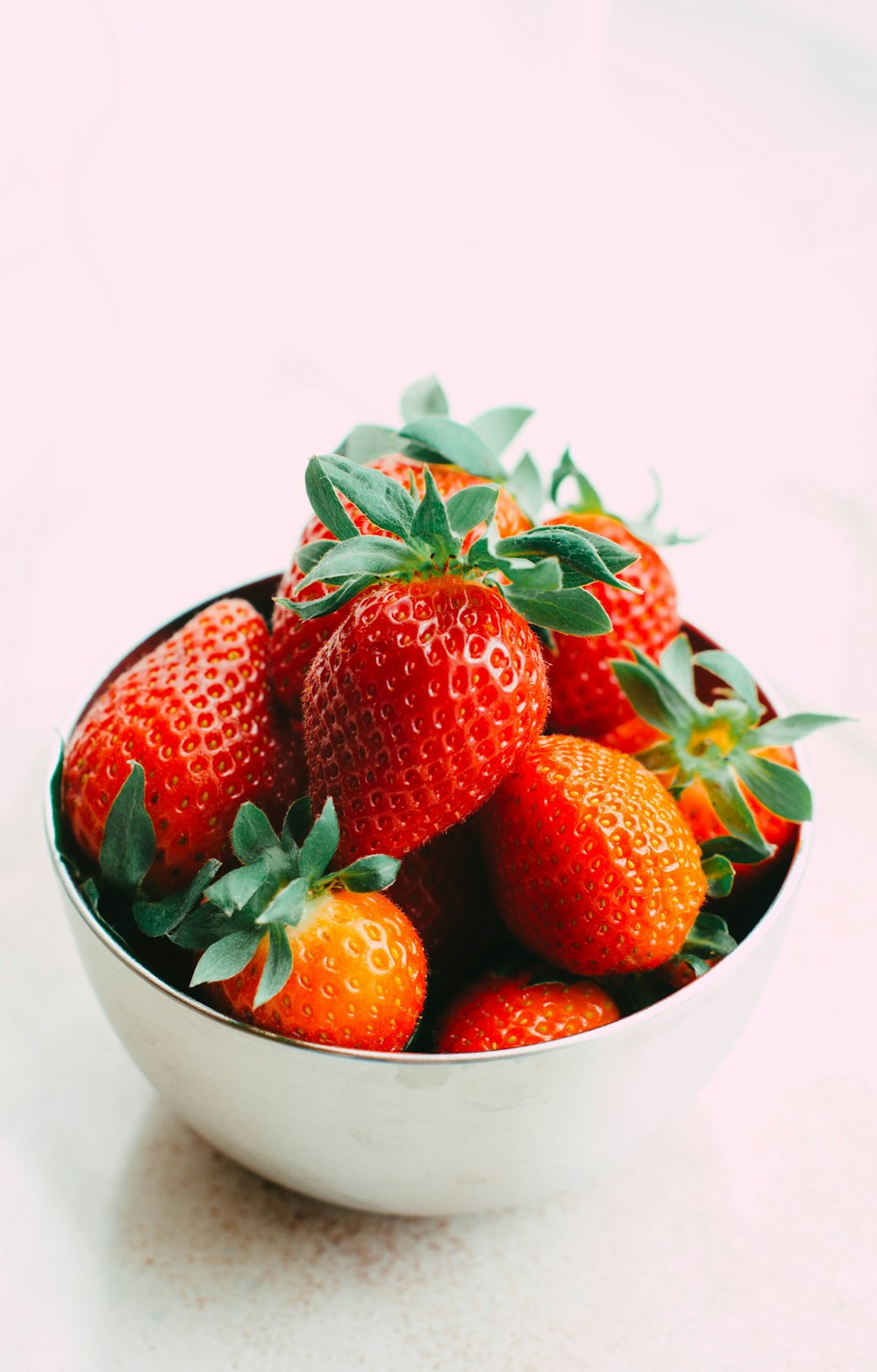 a white bowl filled with lots of ripe strawberries