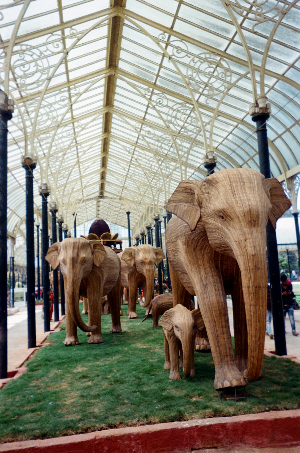 a group of wooden elephants standing on top of a lush green field