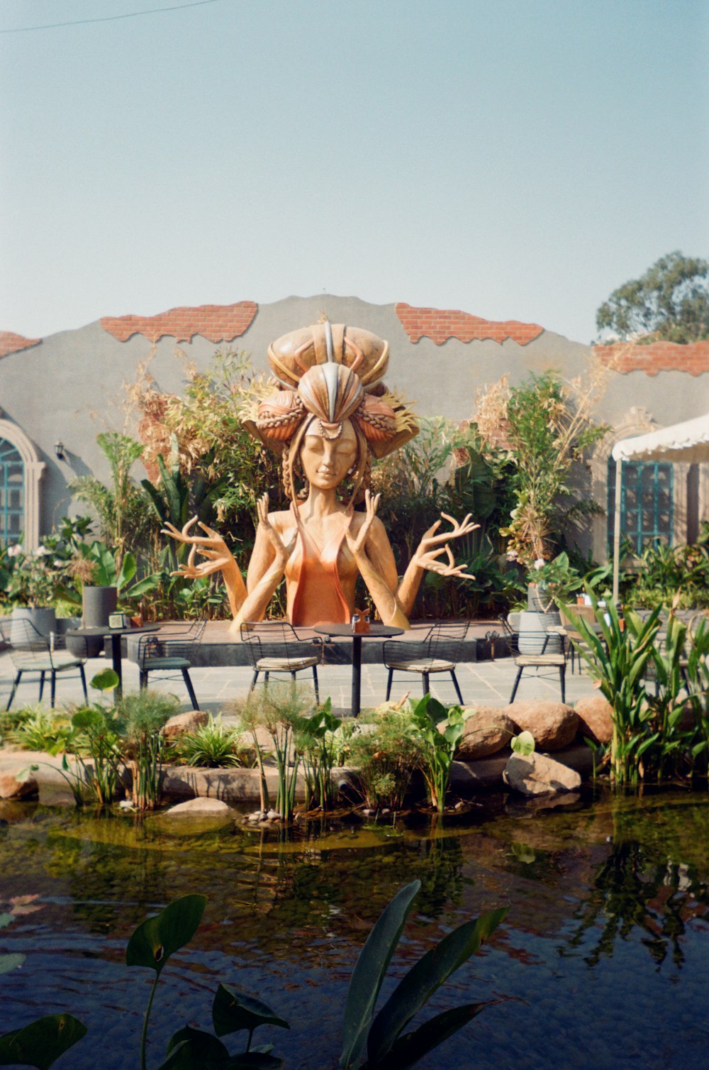 a statue of a woman sitting in front of a pond