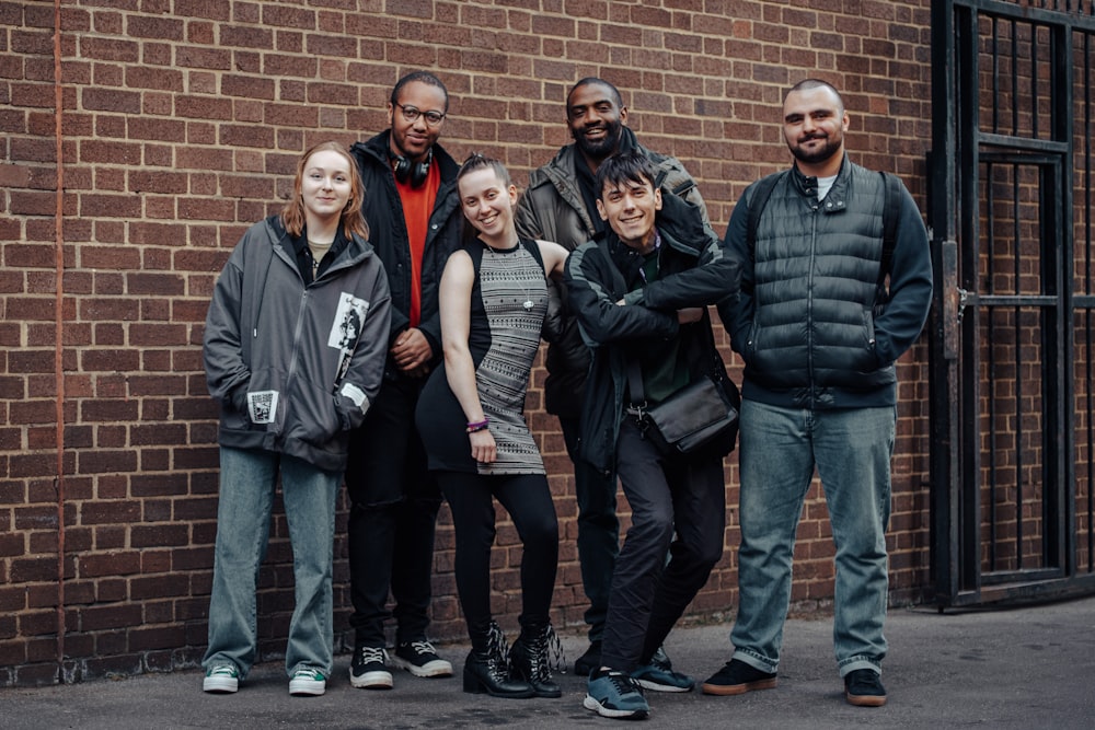 a group of people standing in front of a brick wall