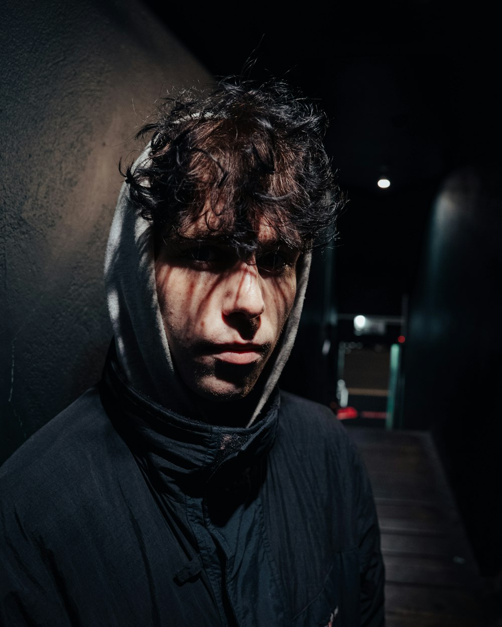 a man wearing a hoodie standing in a dark room