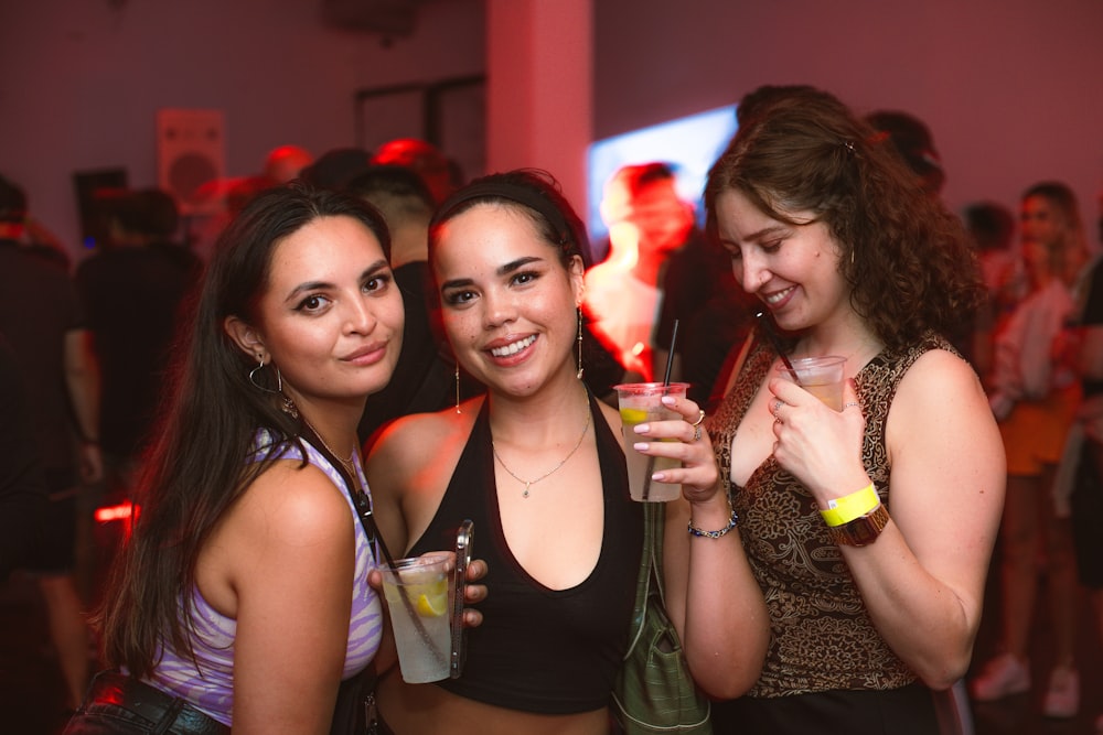 a group of women standing next to each other holding drinks