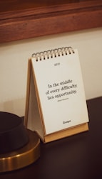 a notepad sitting on top of a desk next to a lamp