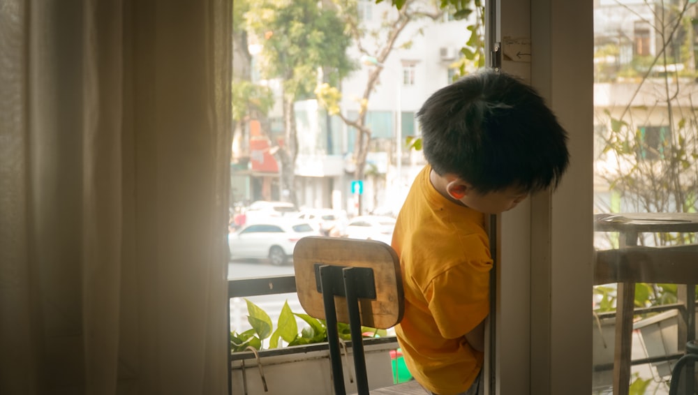a young boy is looking out of a window