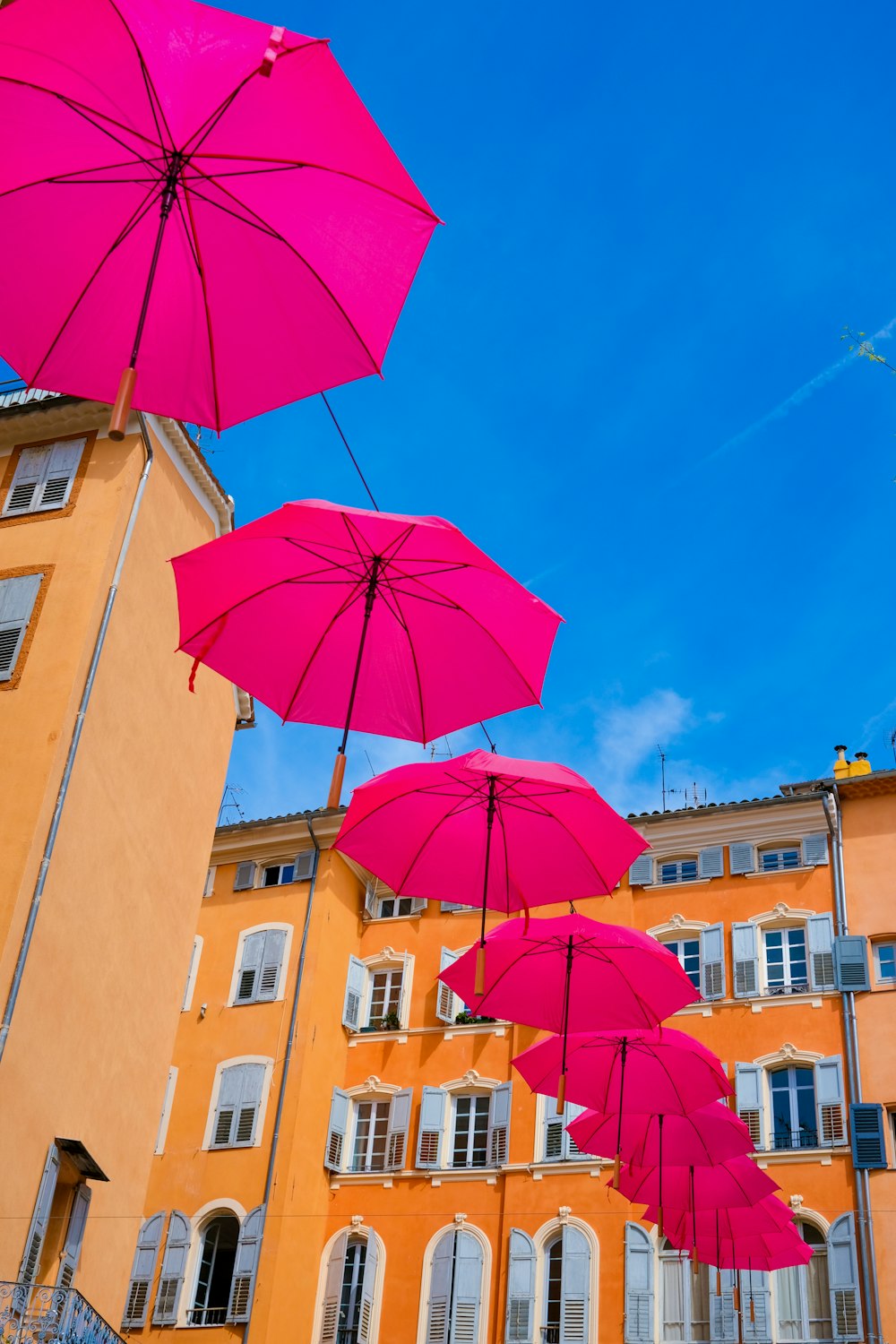a group of pink umbrellas hanging from a building