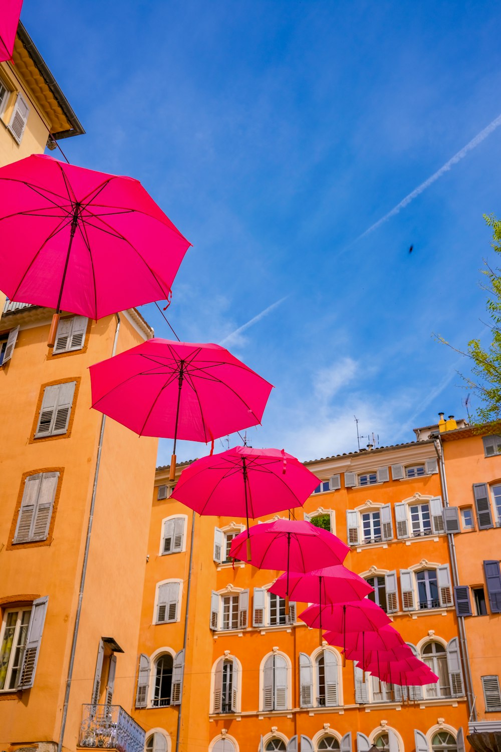 a group of pink umbrellas hanging from the side of a building