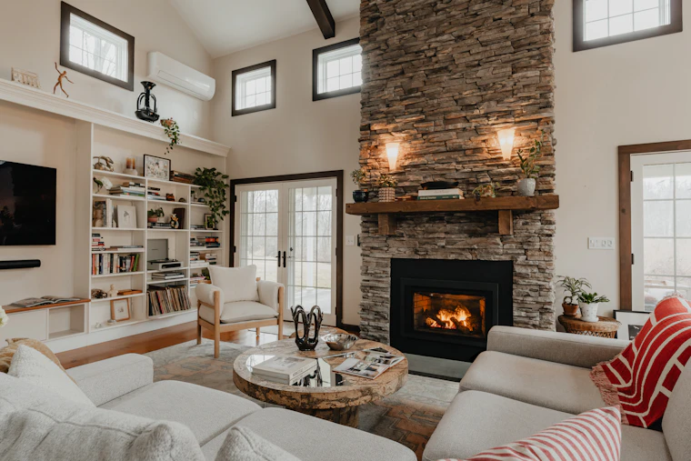 A bright stone fireplace in an open living room.