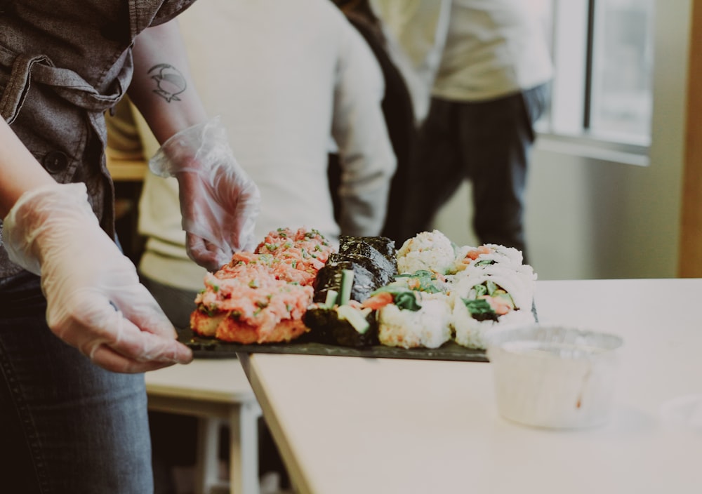 a group of people standing around a table with sushi on it