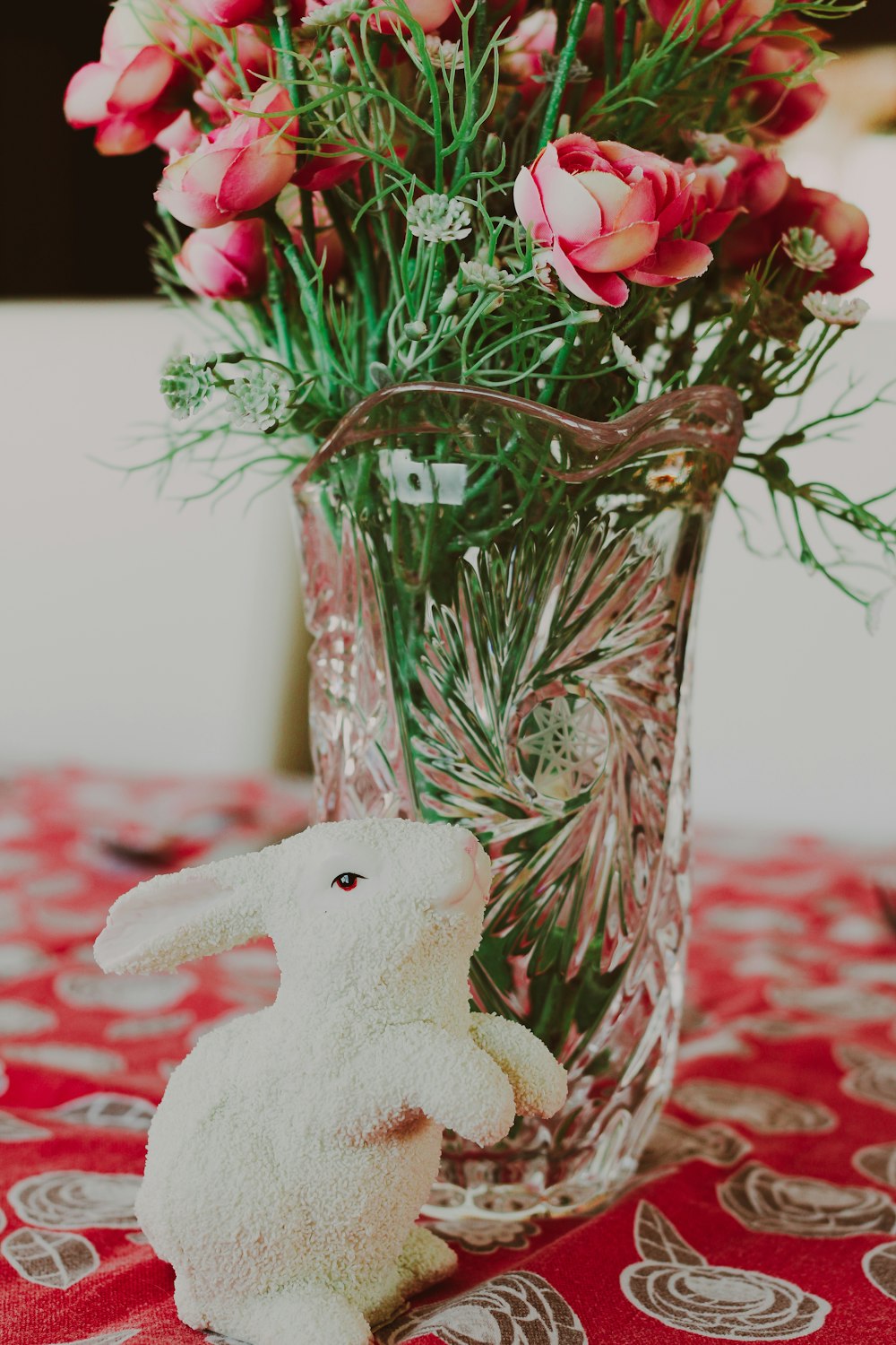 a vase filled with flowers and a white bunny figurine