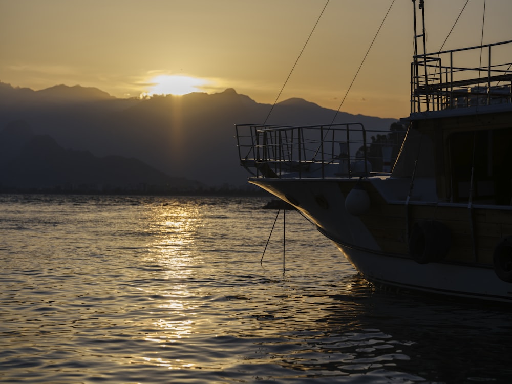 a boat in the water at sunset with mountains in the background