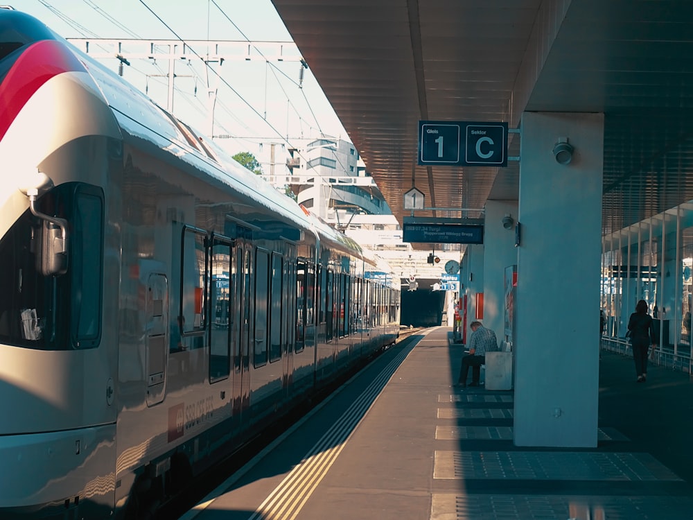 um trem puxando para uma estação de trem ao lado de uma plataforma