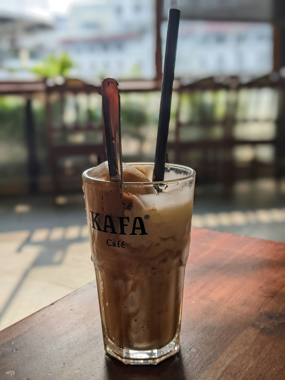 a glass of iced coffee sitting on top of a wooden table