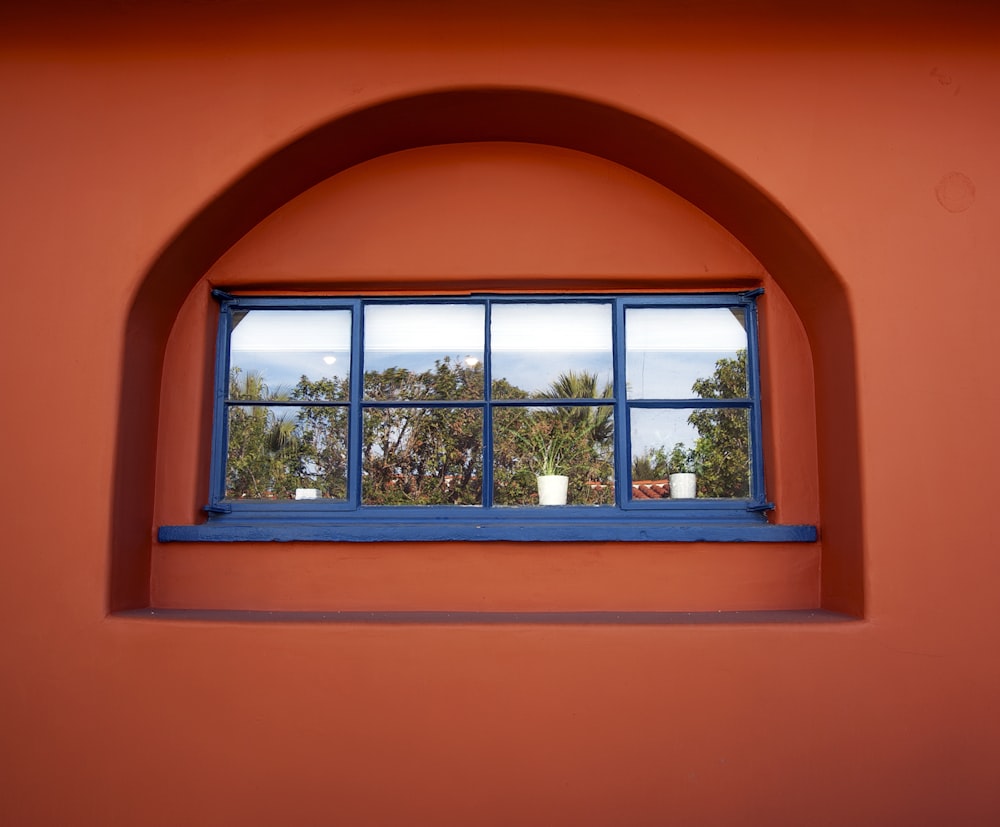 a window with a blue frame and a red wall