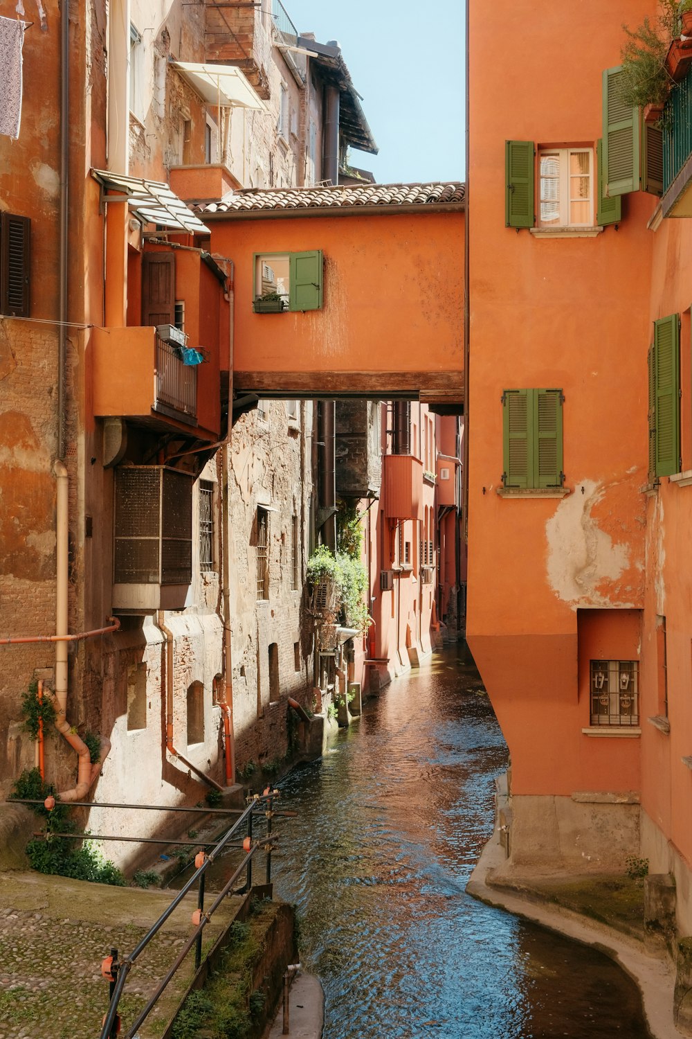 a river running between two buildings with green shutters
