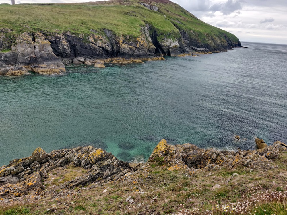 a large body of water sitting next to a lush green hillside