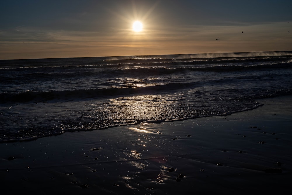 the sun is setting over the ocean waves