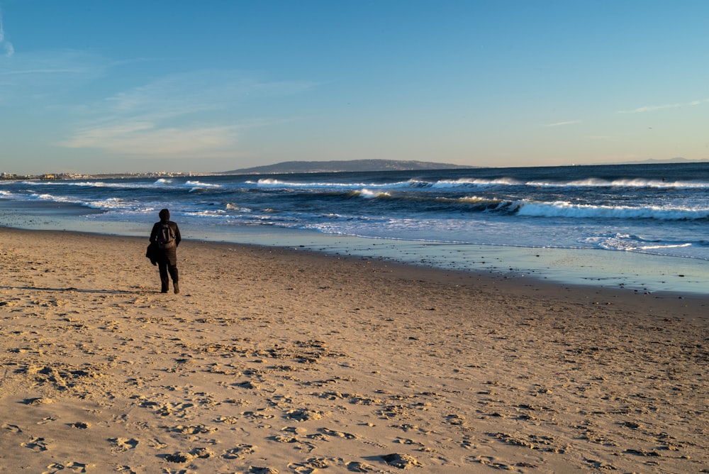 a person standing on a beach with a surfboard