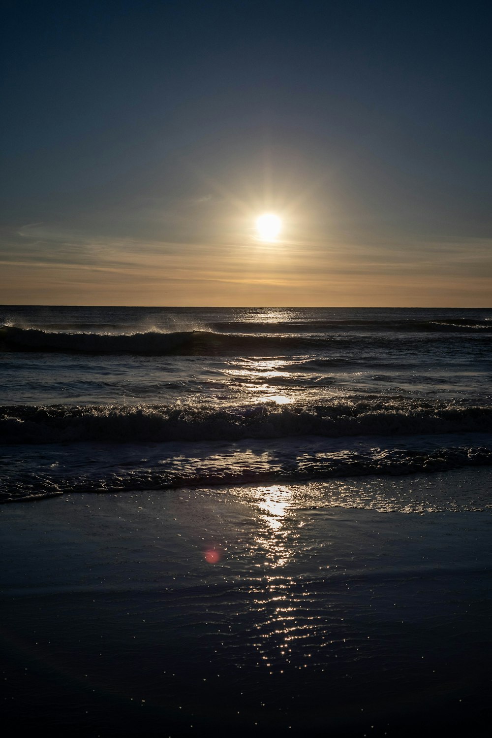 the sun is setting over the ocean on the beach