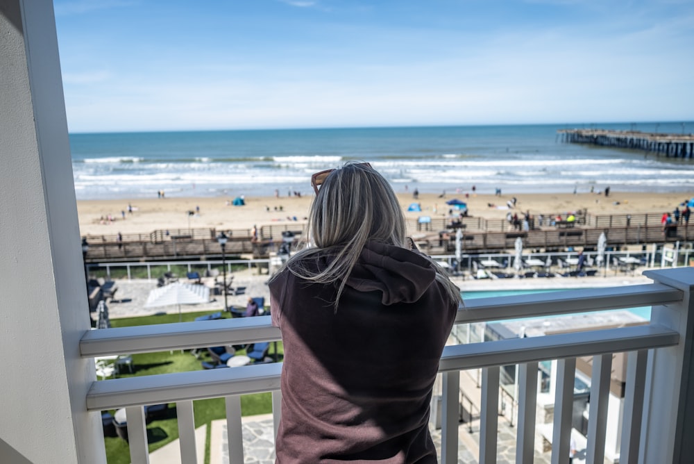 a woman standing on a balcony looking out at the beach