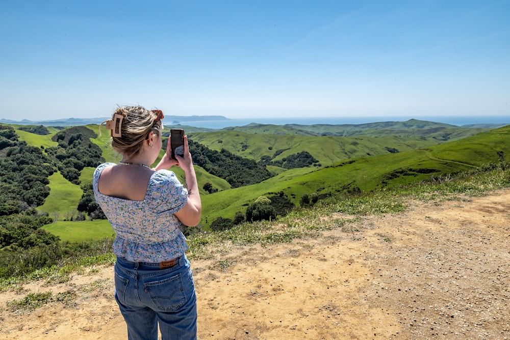a woman taking a picture of the hills