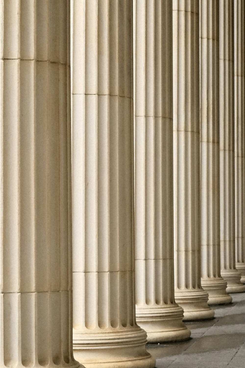 a person sitting on a bench in front of a row of pillars