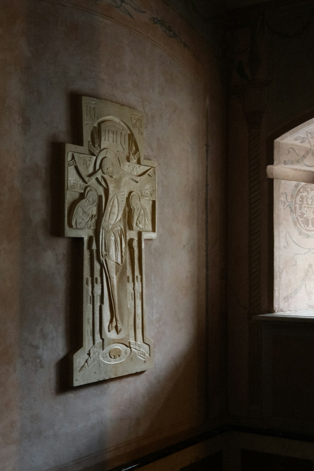 a statue of a person holding a cross on a wall