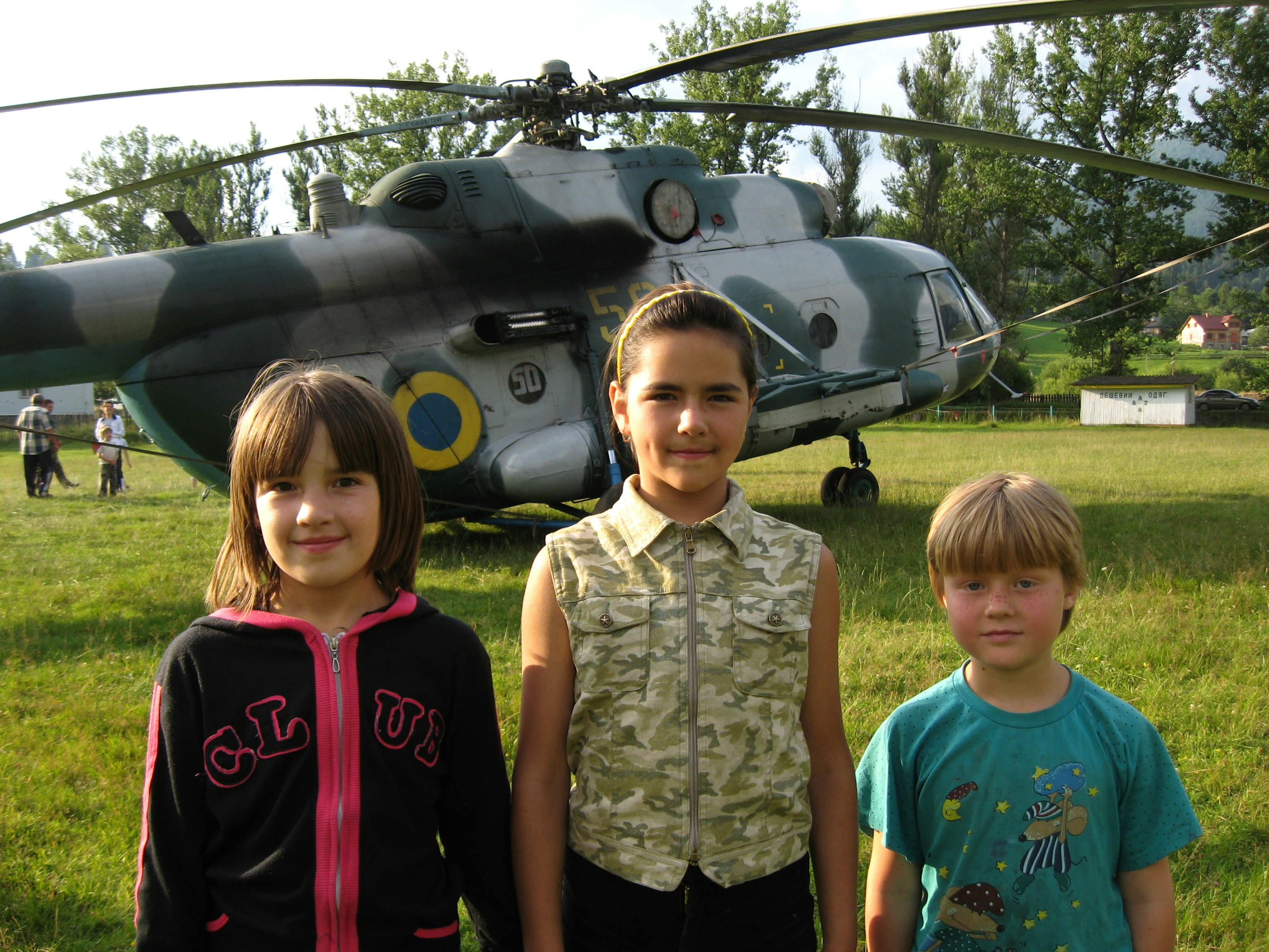 three children standing in front of a helicopter