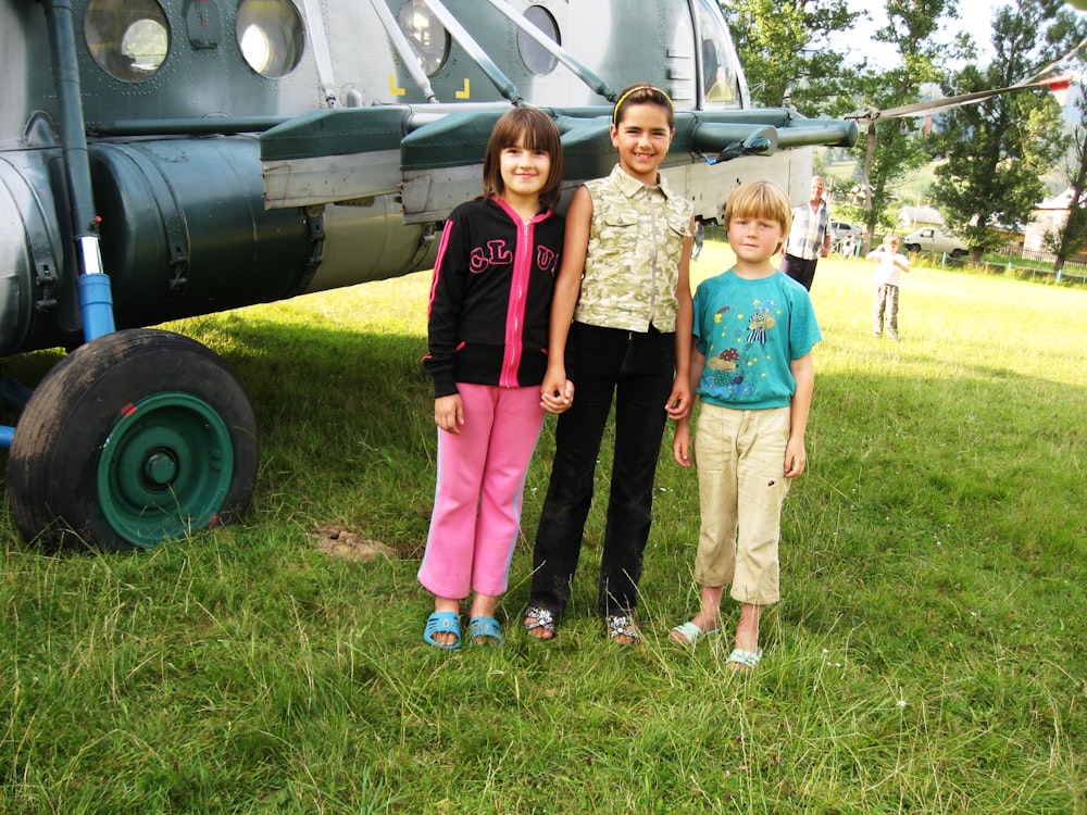 Tres niños parados frente a un avión